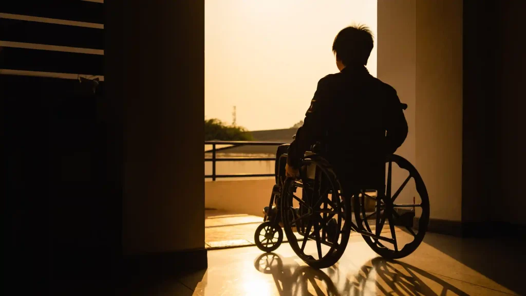 Silhouetted person in a wheelchair looking out at sunset