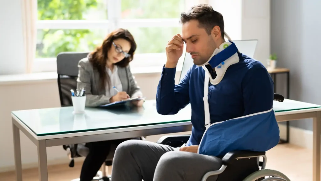 Injured person with a neck brace sitting across from a lawyer during a consultation.